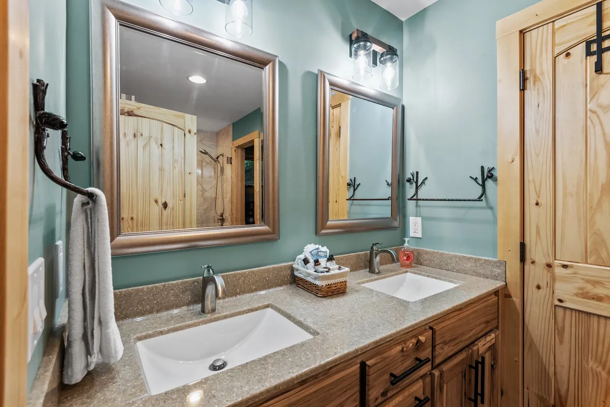 A tranquil bathroom scene with a double granite vanity, stylish mirrors, wooden cabinetry, and decorative touches. The ample counter space and calming atmosphere indicate a space designed for relaxation and convenience.